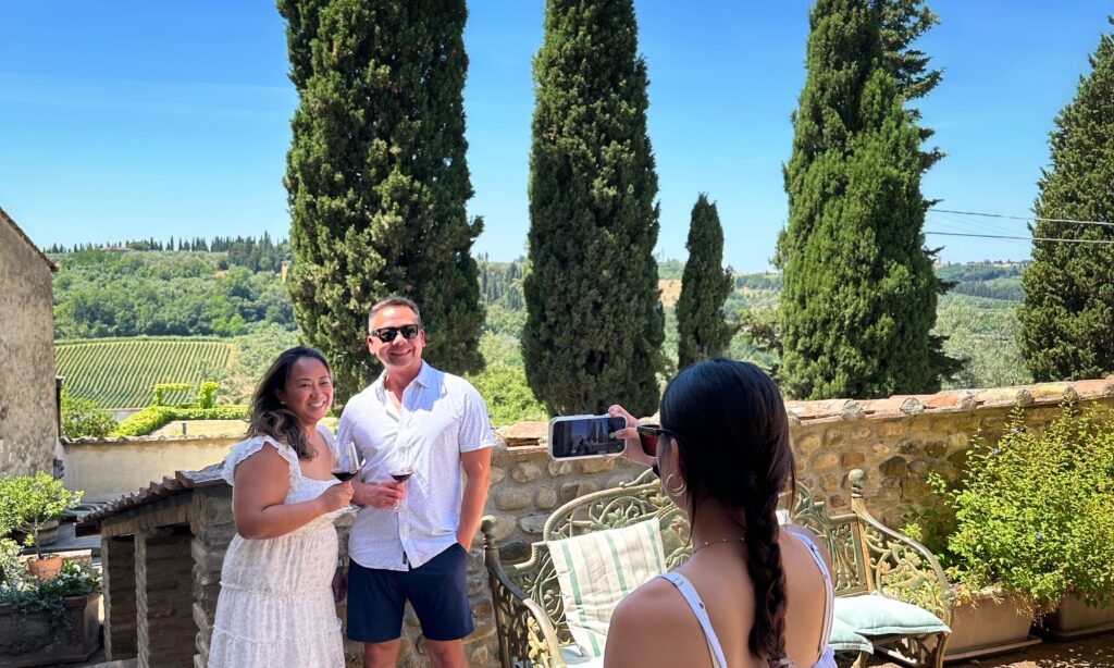 Guests enjoying a private Tuscany wine tour at a family-run winery in Chianti, surrounded by cypress trees and vineyard views.
