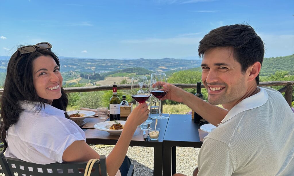 Couple enjoying a wine tasting at a Tuscan winery with vineyard views during a private wine tour from Florence.